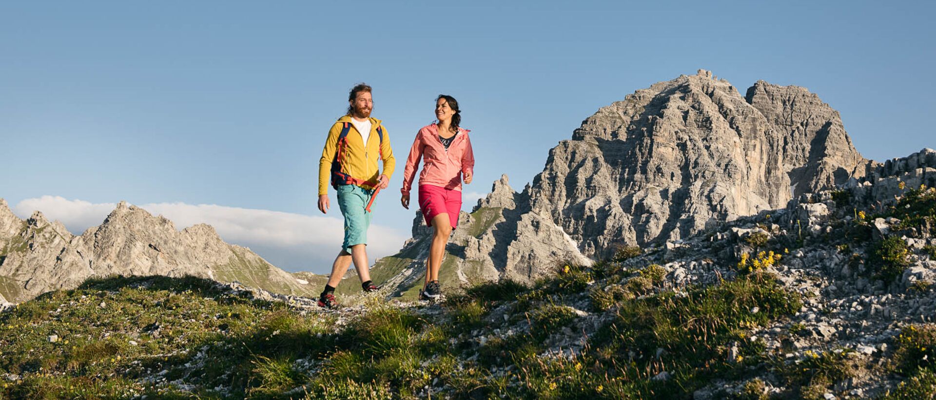 Wanderndes Paar in Berglandschaft vor blauem Himmel