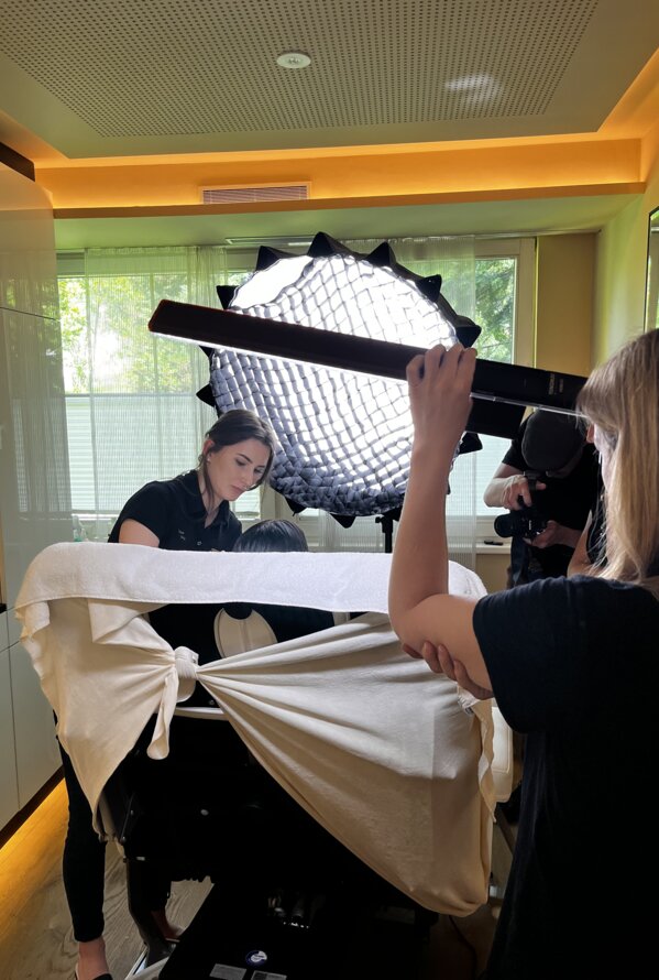 Frau hält Lichtreflektor bei Fotoshooting mit weiterer Frau und Kamera-Mann