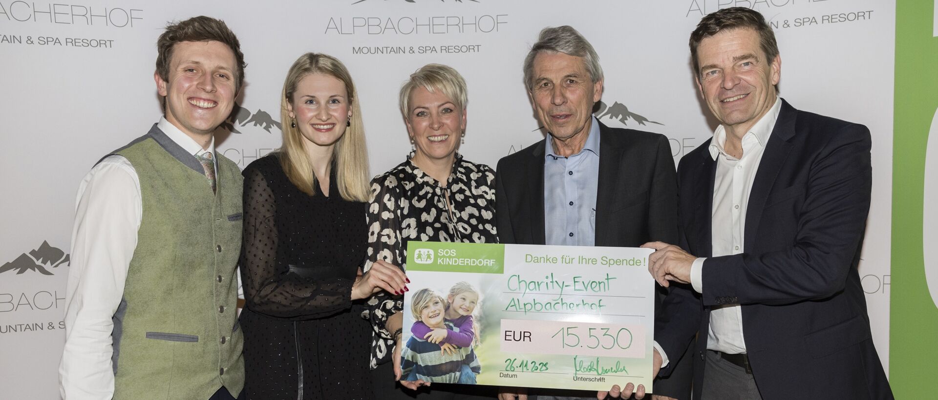 Fünf Personen präsentieren einen übergroßen Spendenscheck vor einer Wand mit Hotellogo