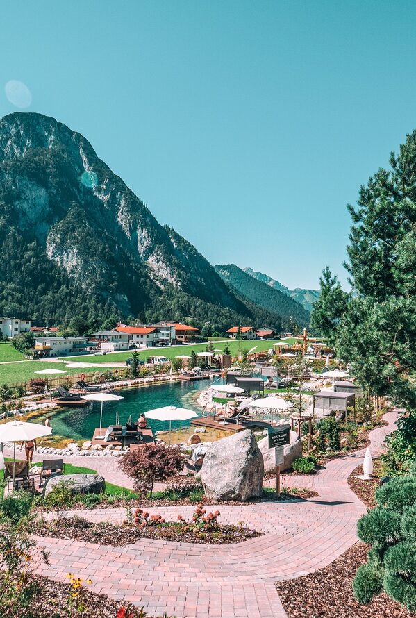 Außenbereich mit Pool, Liegen, Bergpanorama und Alpenrose im Sommer