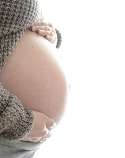Schwangere Frau hält Hände auf ihren Bauch