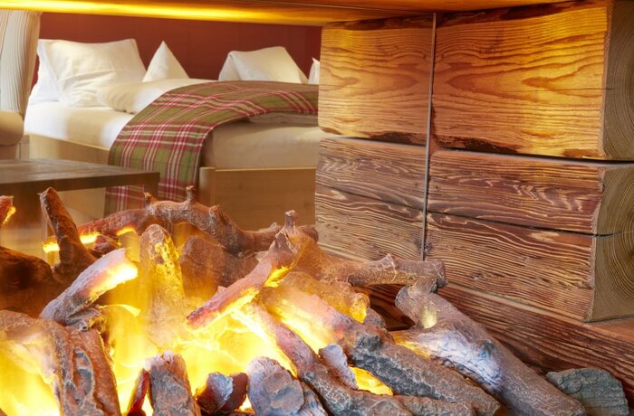 Kaminfeuer im Zimmer mit Holzwand und Bett im Hintergrund