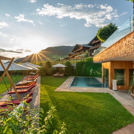 Außenbereich mit Pool, Sonnenliegen und Bergblick bei Sonnenuntergang
