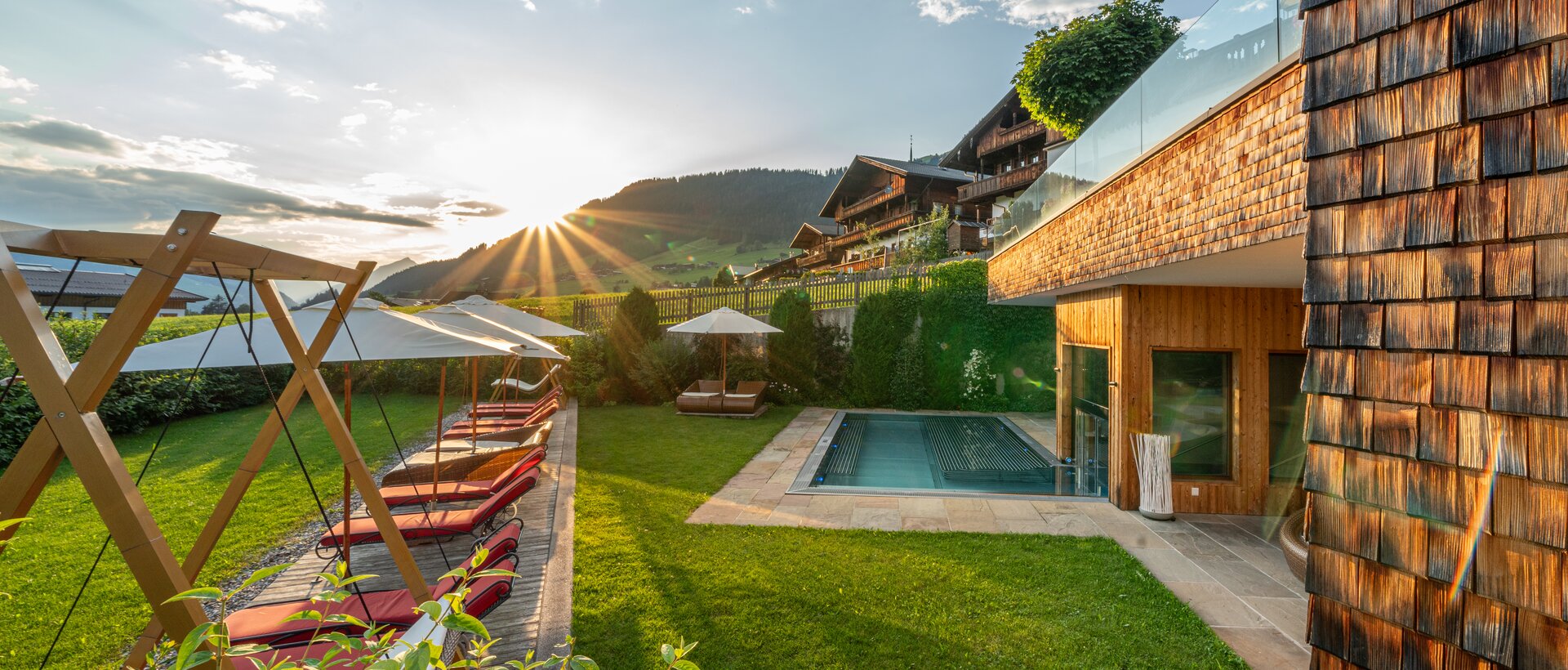 Outdoor area with pool, sun loungers and mountain view at sunset