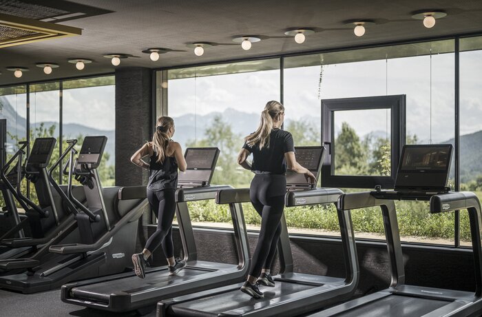 Zwei Frauen trainieren auf Laufbändern in einem Fitnessstudio mit Panoramafenster