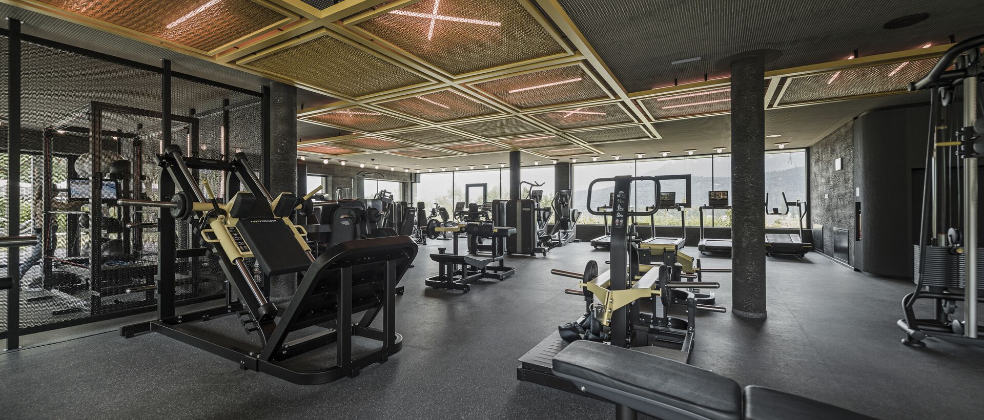 Fitnessstudio mit schwarzen Geräten und Deckenkonstruktion mit gelben Akzenten