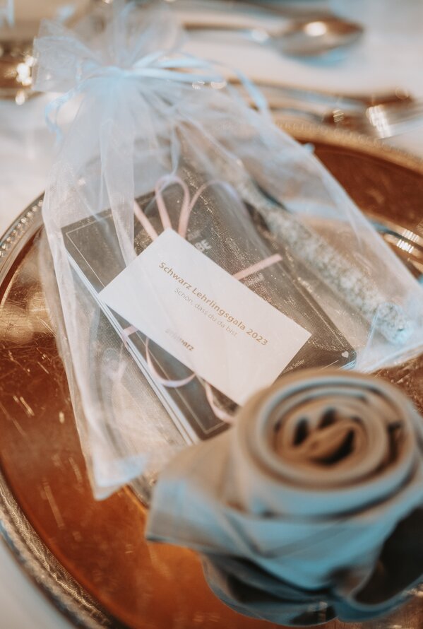 Silberteller mit Besteck, Serviette und Gastgeschenk in Organzabeutel