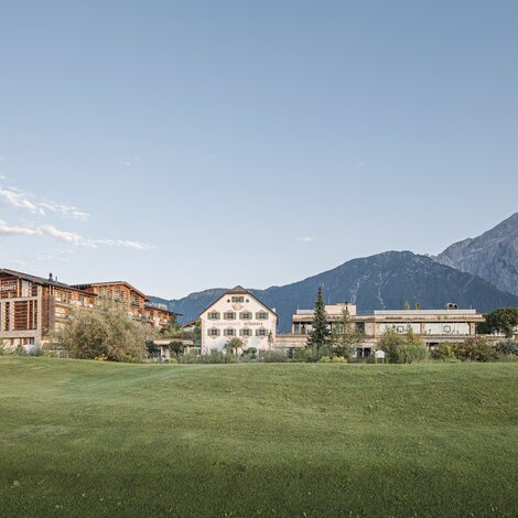 Alpenresort Schwarz mit Bergen im Hintergrund unter blauem Himmel
