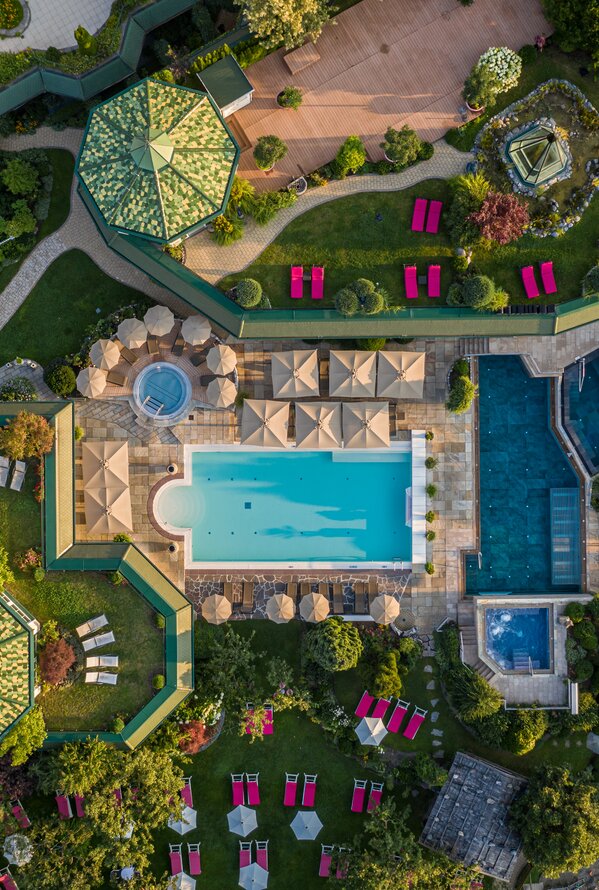 Luftaufnahme einer großzügigen Wellness- und Gartenanlage mit Pools und Ruhebereichen.