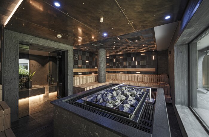 Dunkle Sauna mit Steinofen und Holzbänken