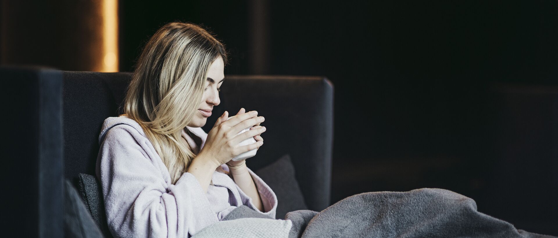 Frau entspannt im Wellnesshotel mit einer Tasse Tee in gemütlicher Lounge-Atmosphäre.