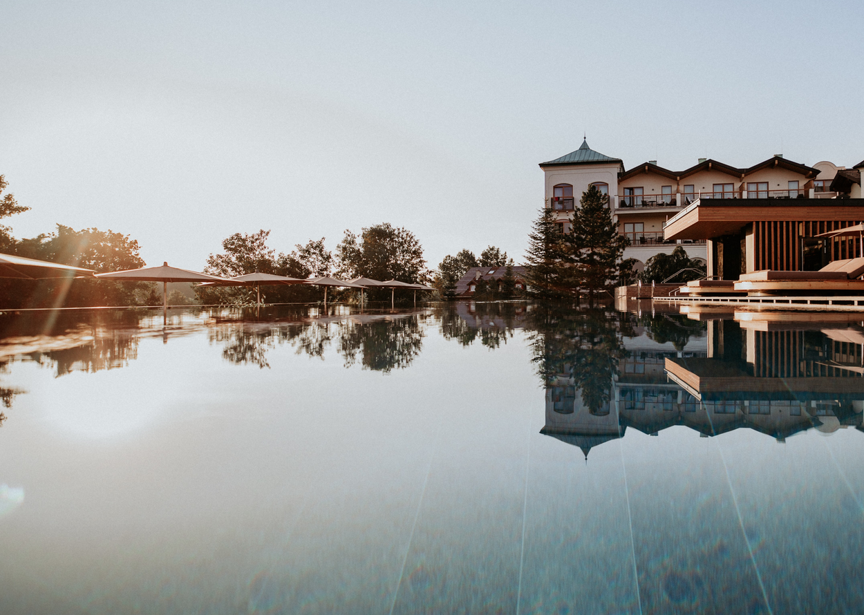 Ein ruhiger Pool spiegelt ein Hotel und den Abendhimmel wider.