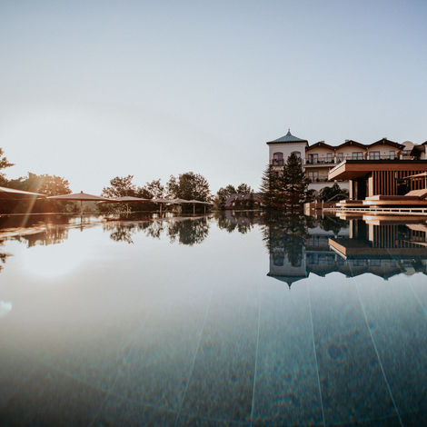 Ein ruhiger Pool spiegelt ein Hotel und den Abendhimmel wider.