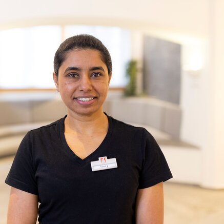 Freundliche Mitarbeiterin im Wellnessbereich mit professioneller Spa-Bekleidung.