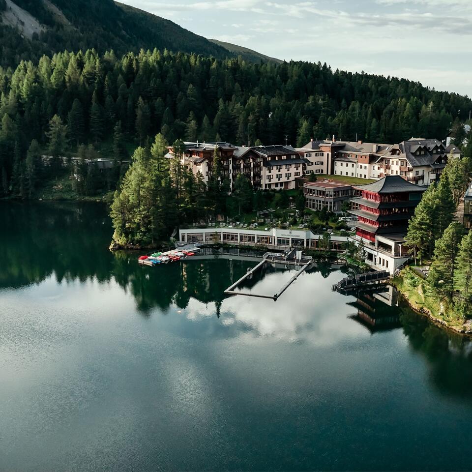 Hotelanlage am See, umgeben von Wald und Bergen