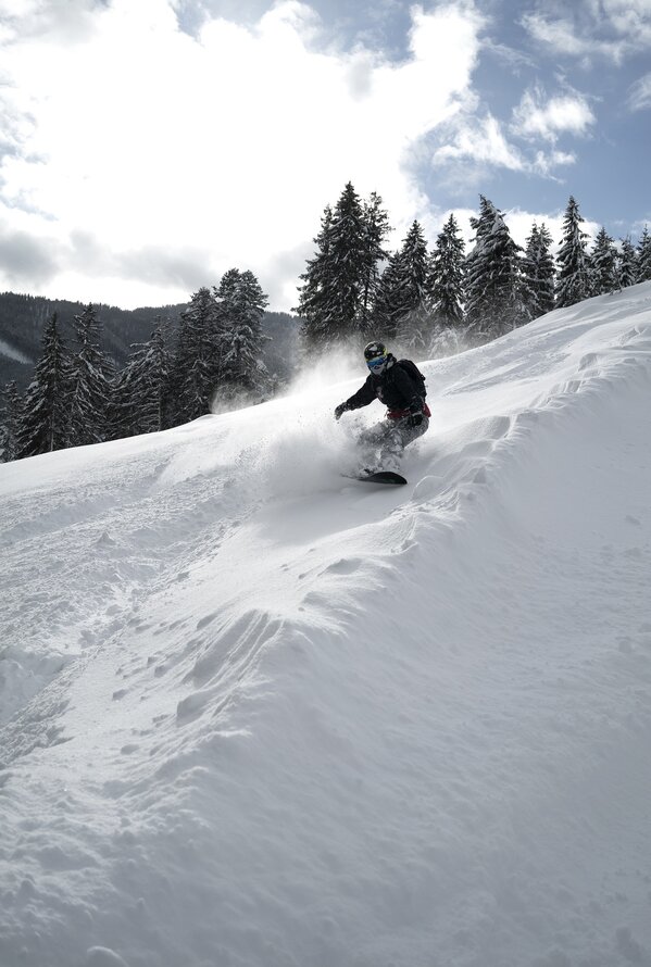 Snowboarder fährt im Winter einen schneebedeckten Hang hinunter