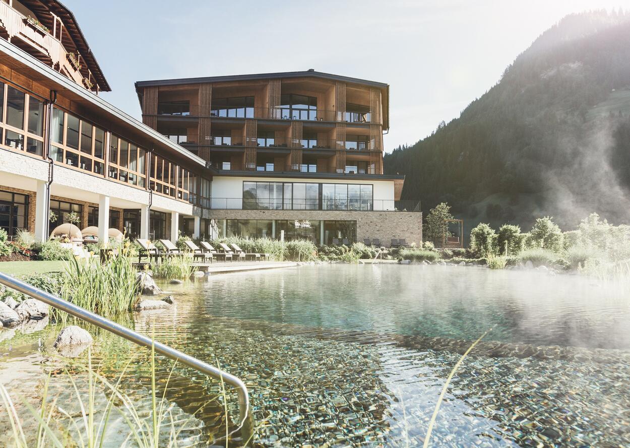 Hotel Nesslerhof mit Naturpool und Bergpanorama im Hintergrund