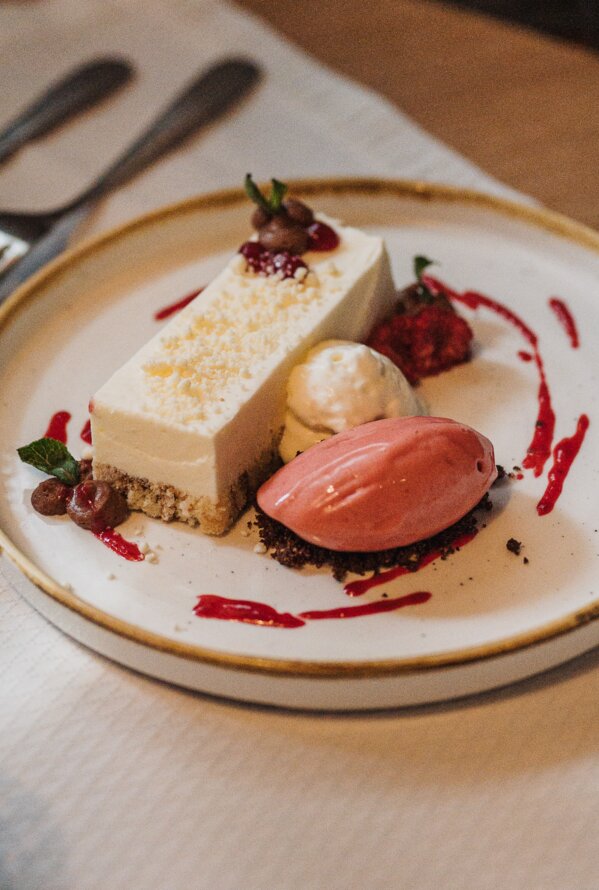 Ein elegant angerichtetes Dessert mit Eis und Beeren steht auf einem Restauranttisch.