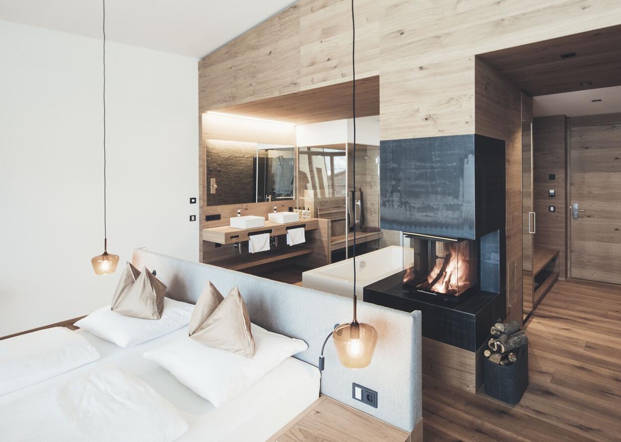 Helle Suite mit Doppelbett, Kamin und Blick auf ein Badezimmer mit Doppelwaschbecken