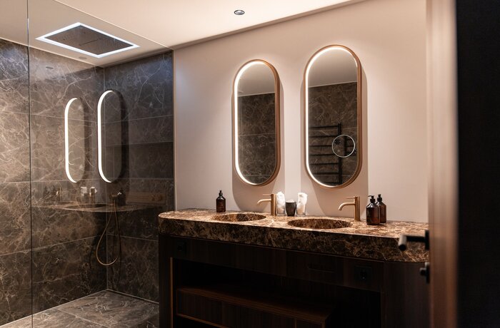 Modernes Badezimmer mit zwei Waschbecken und ovalen Spiegeln mit Beleuchtung