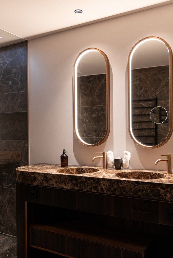 Modernes Badezimmer mit zwei Waschbecken und ovalen Spiegeln mit Beleuchtung