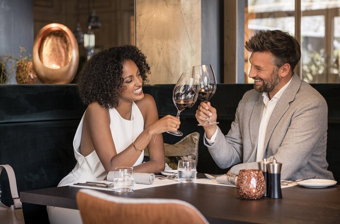 Lachendes Paar stößt mit Rotwein im Restaurant an