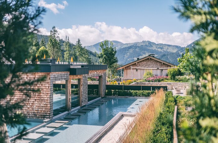 Außenpool mit alpinem Panorama und modernem Wellnessbereich.
