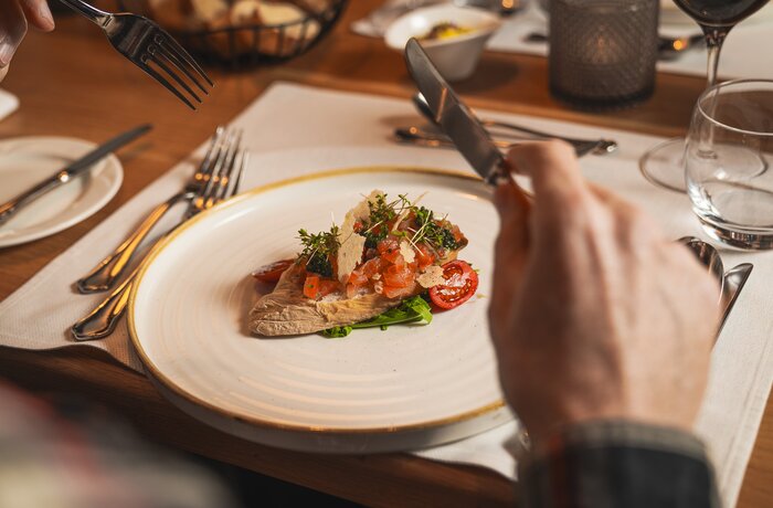 Fein angerichtete Vorspeise auf einem Restauranttisch mit Besteck und gedecktem Ambiente