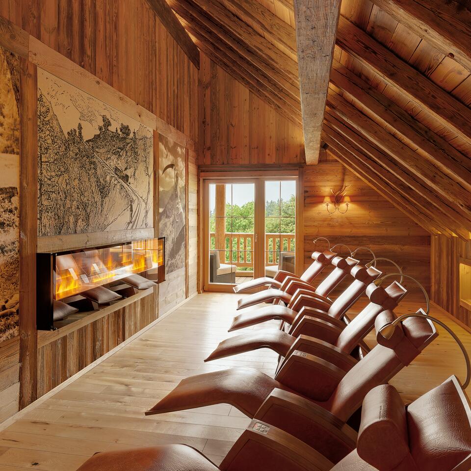 Holzvertäfelter Ruheraum mit Liegen, Kamin und Bergblick im Wellnesshotel Alpenrose