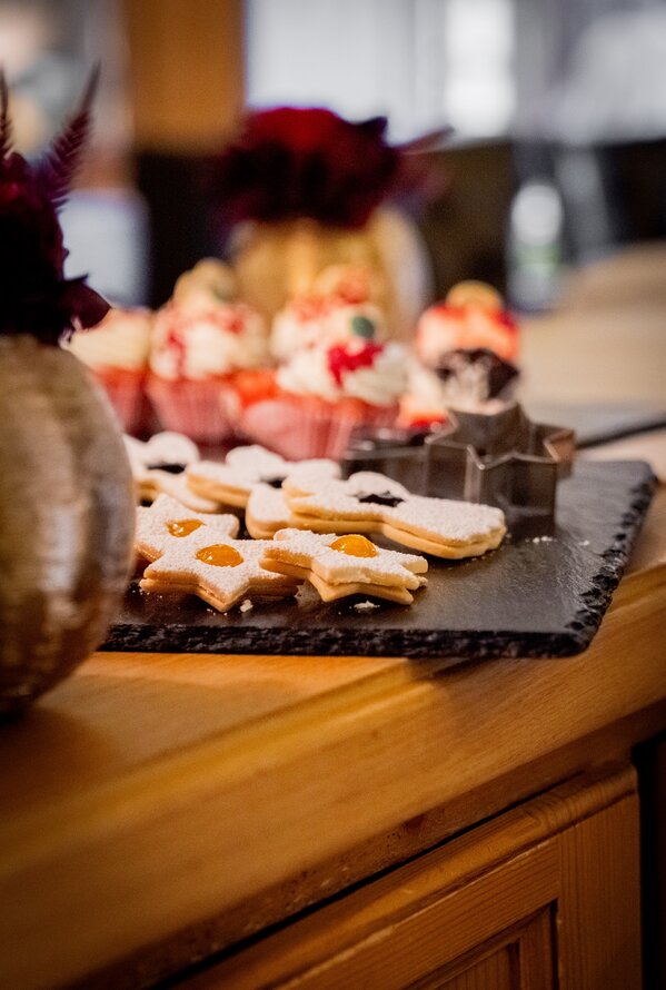 Sternförmige Kekse mit Marmelade und Muffins auf einem dunklen Serviertablett