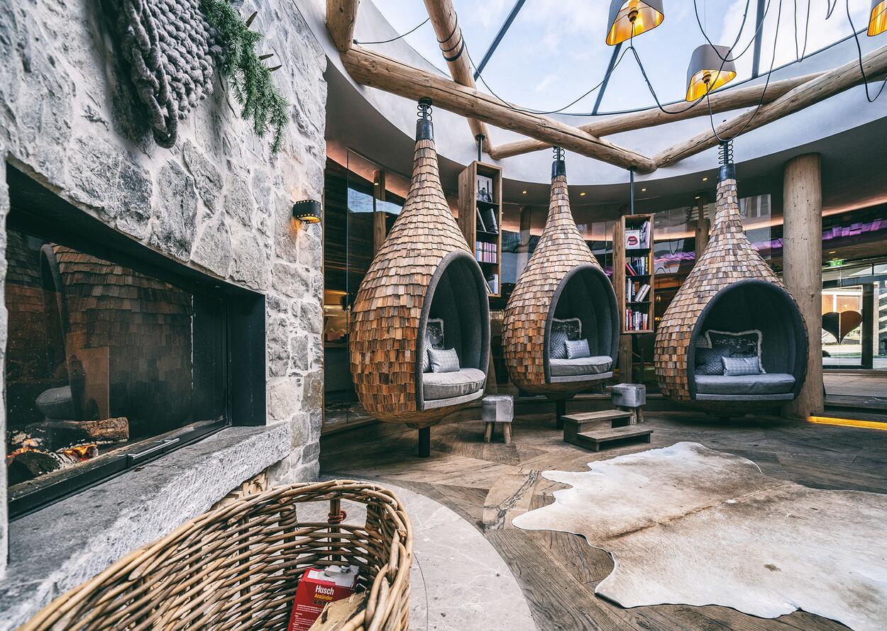 Hotel-Lounge mit Hängekörben, Kamin und Bücherregalen