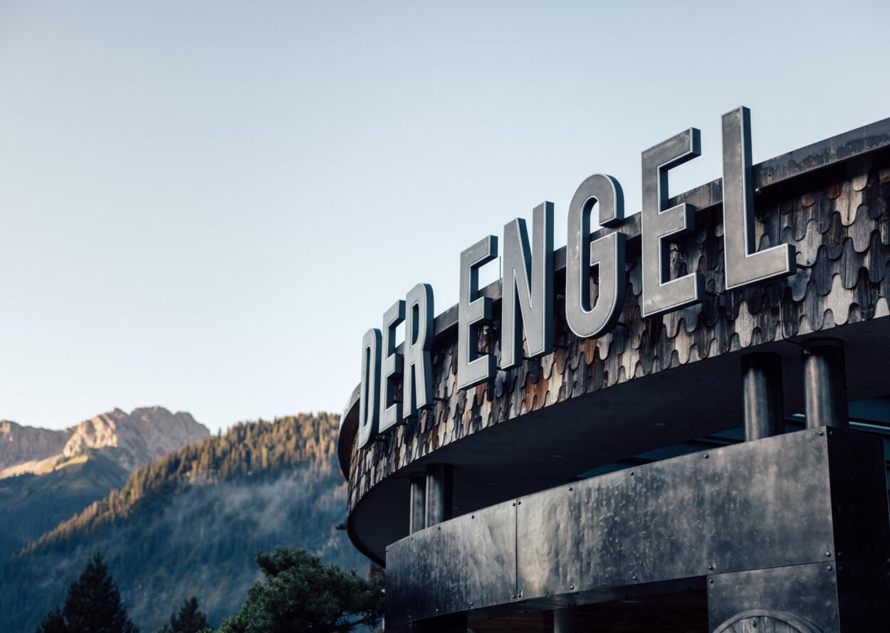 Außenansicht Hotel "Der Engel" mit großem Schriftzug vor Bergkulisse