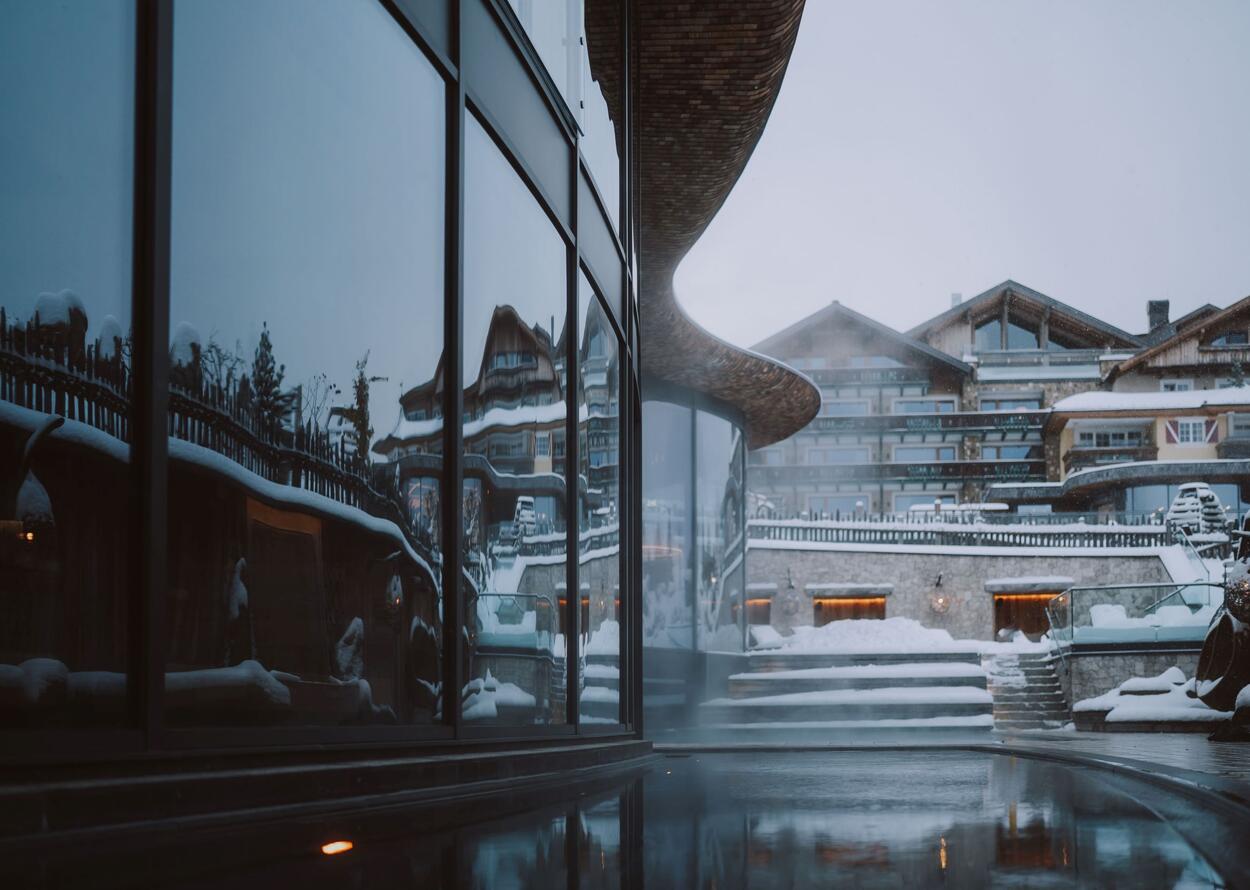 Hotelaußenansicht im Winter mit Schnee und Spiegelung eines Gebäudes in den Fenstern