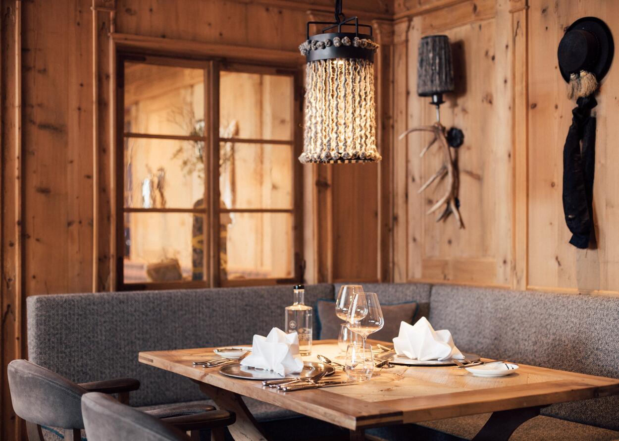 Holzvertäfelte Stube mit Tisch, Gläsern, Lampe und Fenster