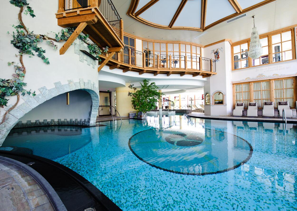 Innenpool mit türkisfarbenem Wasser in Wellnesshotel mit Galerie und Holzelementen