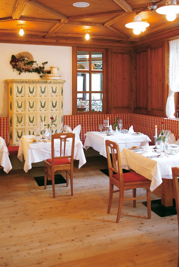 Restaurantbereich mit gedeckten Tischen, Kachelofen und Holzvertäfelung im Wellnesshotel Watherhof