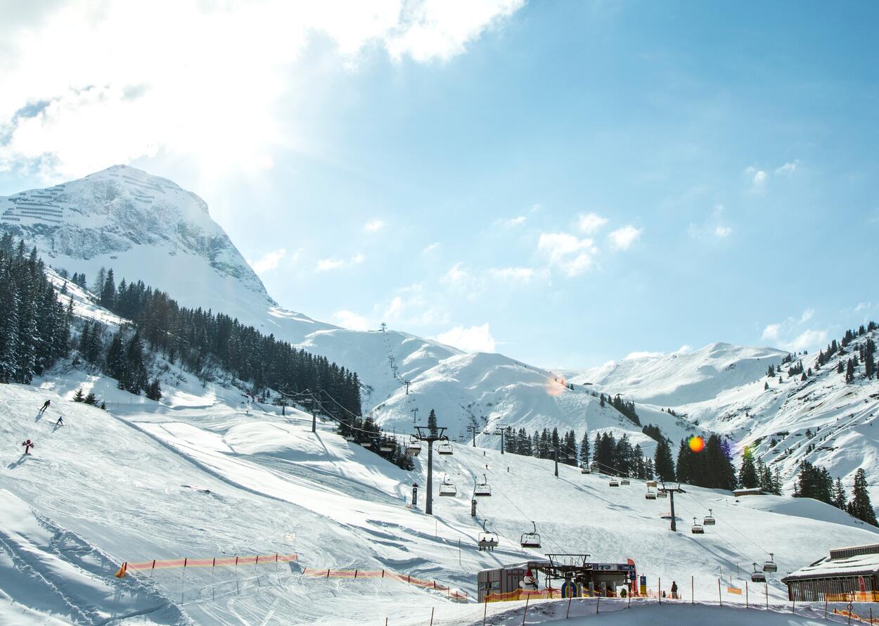 Verschneite Skipiste in Arlberg mit Liftanlagen und strahlendem Sonnenschein