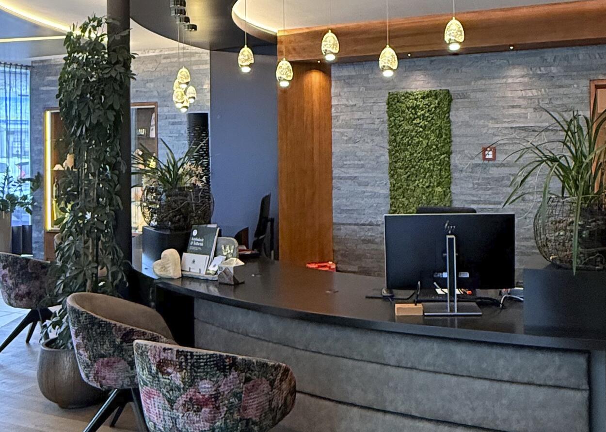 Moderne Hotelrezeption mit stilvoller Einrichtung, Pflanzen und warmem Licht.