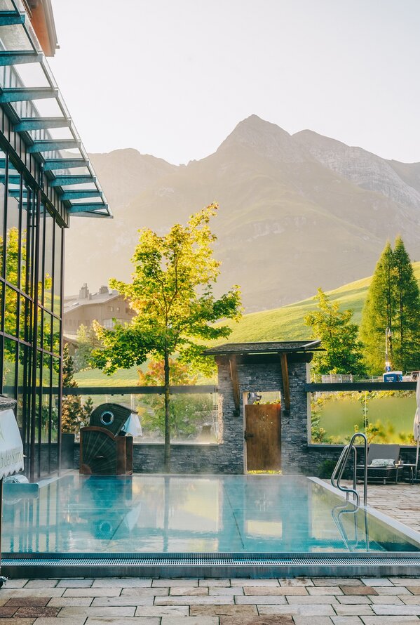 Outdoorpool mit kristallklarem Wasser und traumhaftem Alpenpanorama für pure Entspannung.