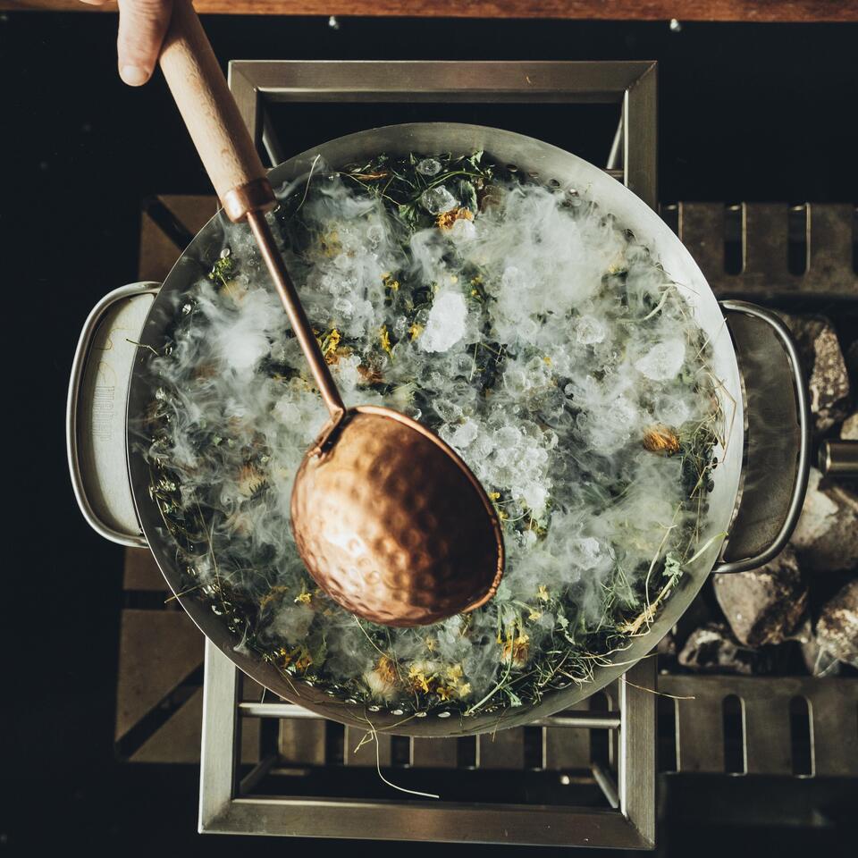Großer Topf mit Eis, Kräutern und einem Schöpflöffel von oben