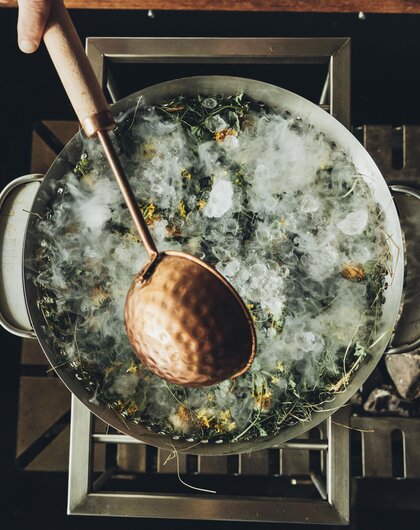 Großer Topf mit Eis, Kräutern und einem Schöpflöffel von oben