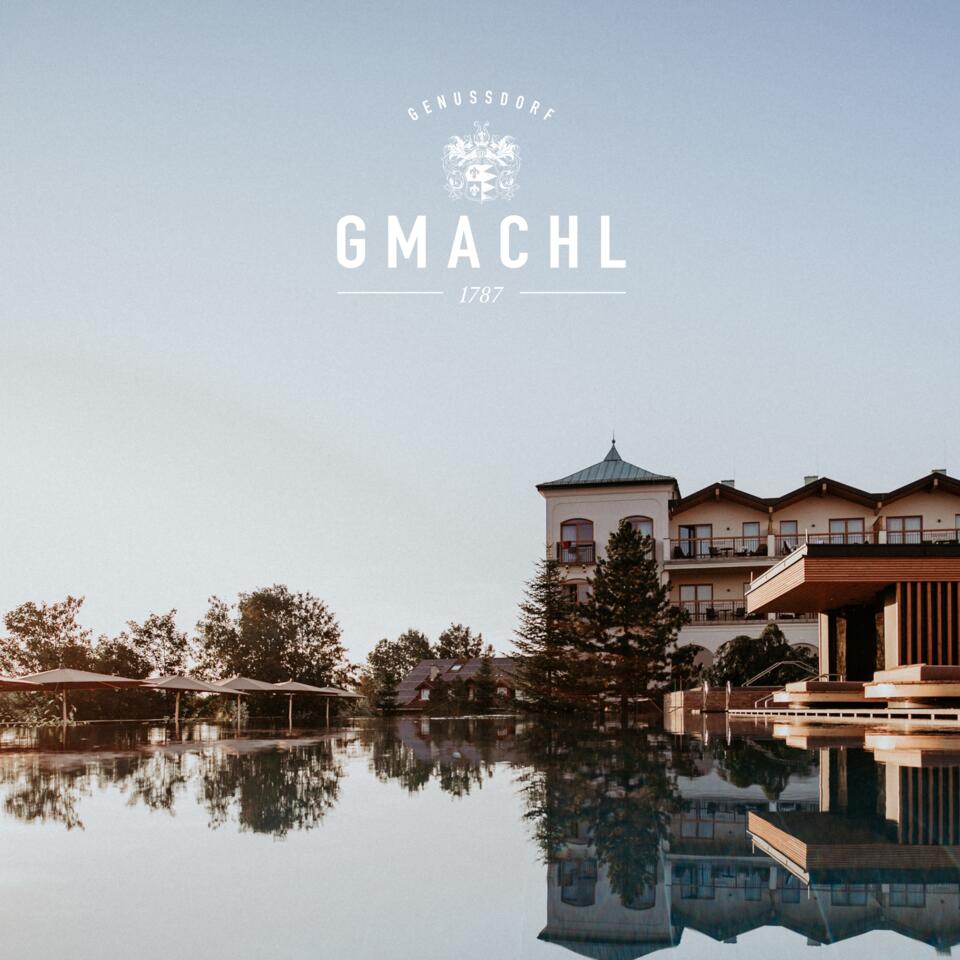 Spiegelung eines Gebäudes im Wasser unter blauem Himmel mit Logo Gmachl