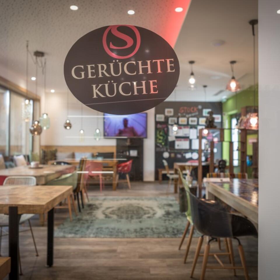 Innenansicht des Restaurants Gerüchte Küche durch eine Glastür mit Logo