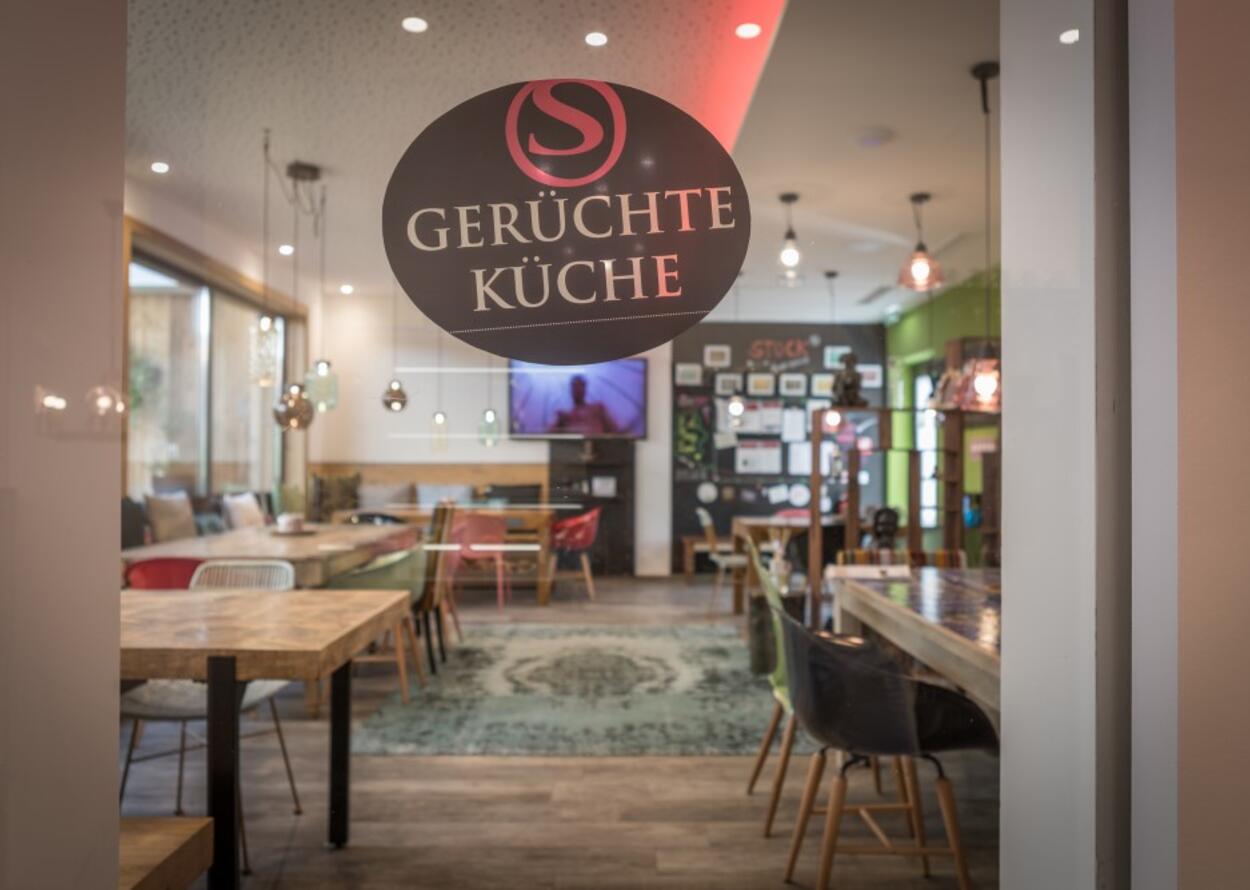 Innenansicht des Restaurants Gerüchte Küche durch eine Glastür mit Logo