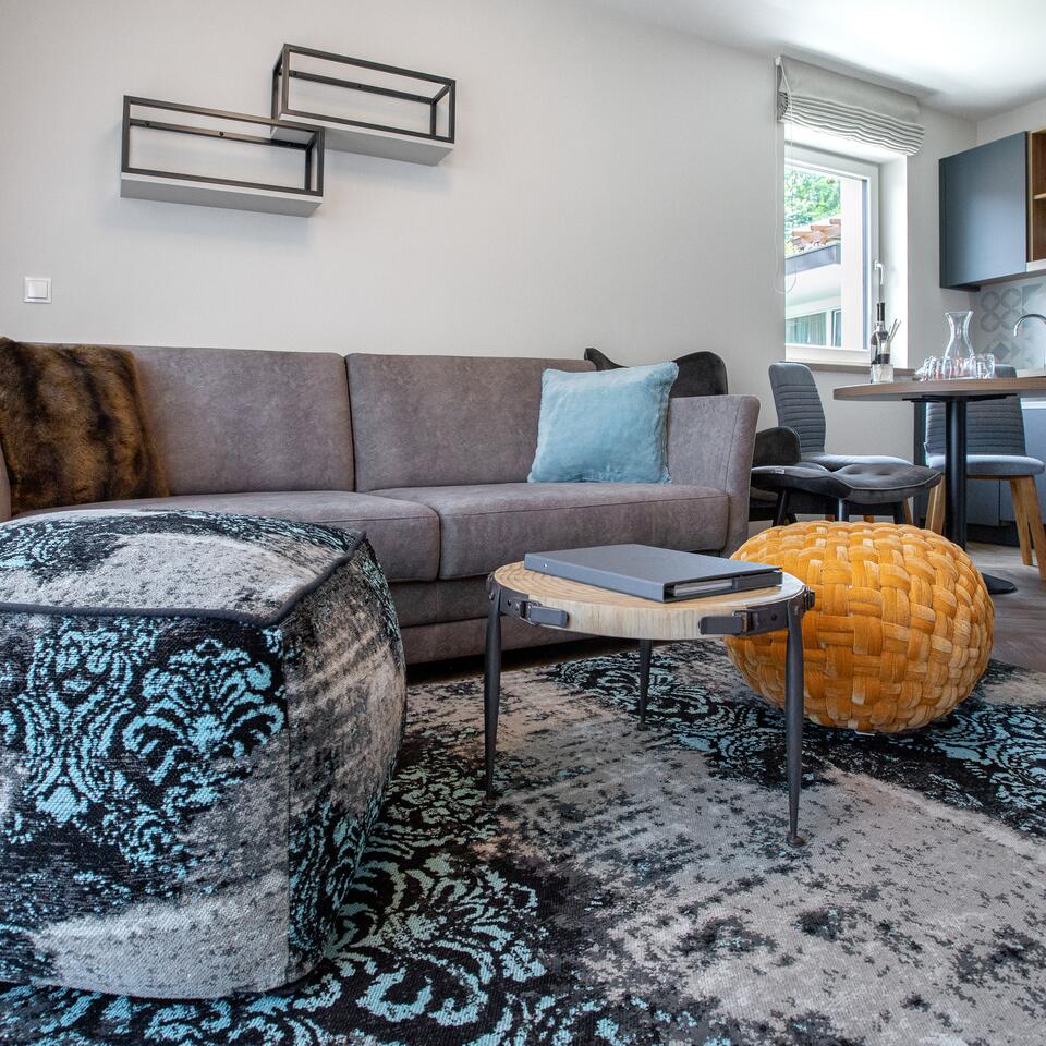 Wohnzimmer mit grauem Sofa, gemustertem Teppich und dekorativen Kissen